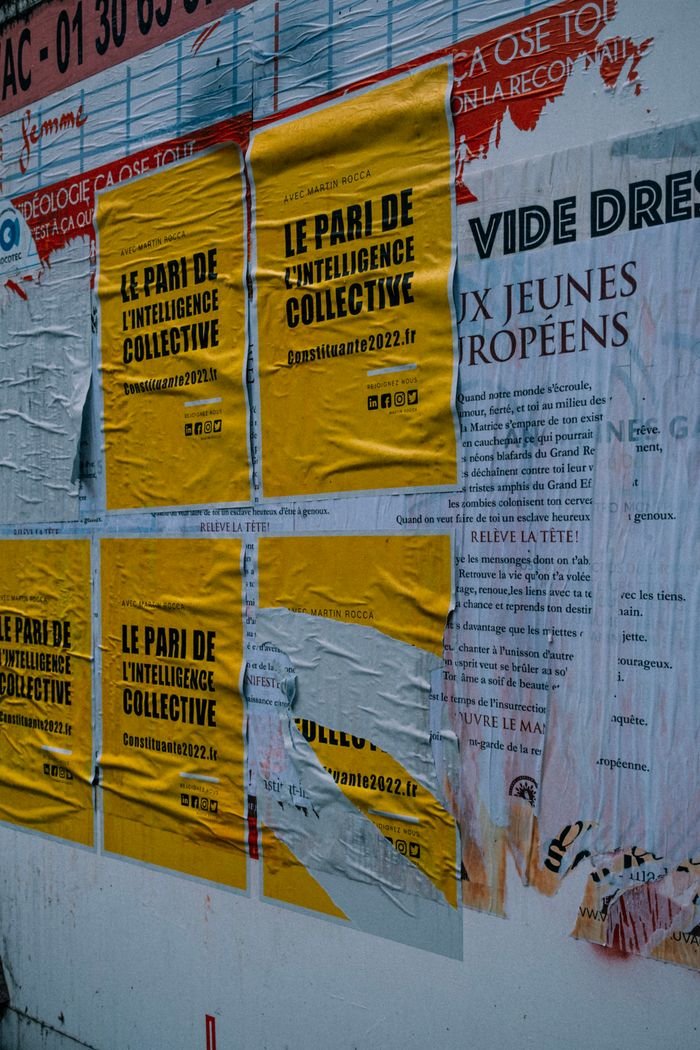Vertical shot of various posters on an urban wall, emphasizing street advertisement.