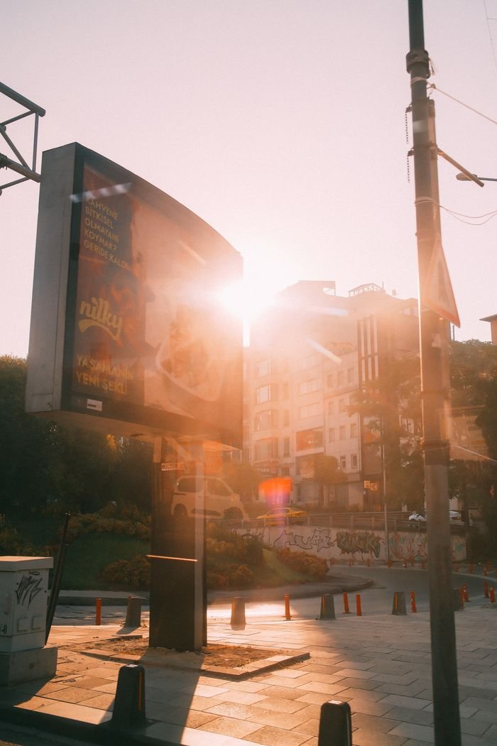 Sunrise over a cityscape with a prominent billboard and urban architecture in view.