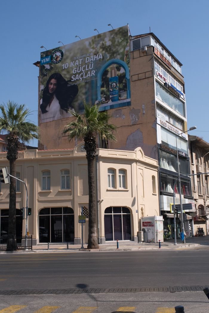 Street view of a building with a large billboard in Izmir, Türkiye.